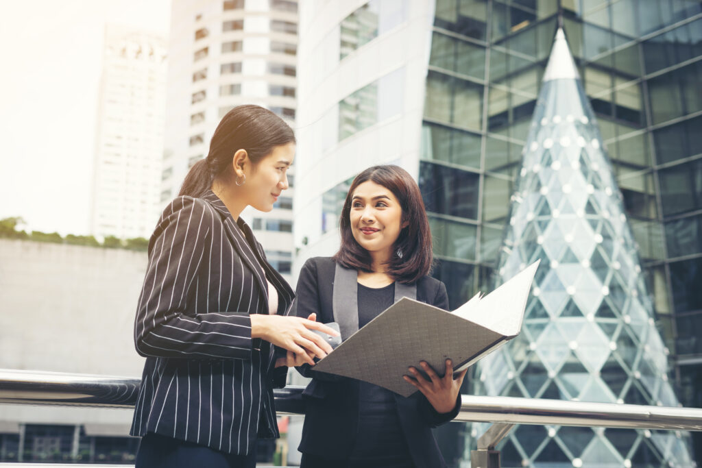 Businesswomen discussing over paperwork together against railing